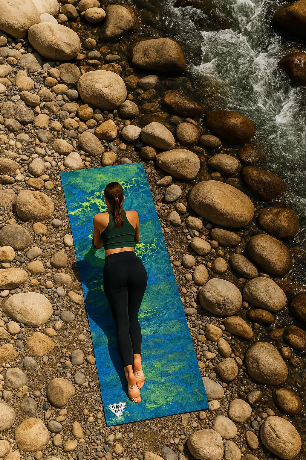 Person practicing yoga on a mat by a rocky stream